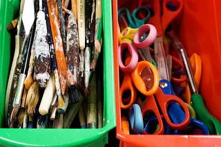 In zwei Plastikwannen liegen Bastelsachen (Scheren und farbverschmierte Pinsel).