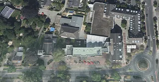 Luftaufnahme des kirchlichen Gebäudecampus in Hösel, mit angrenzenden Straßen, Parkplätzen und Grünflächen.