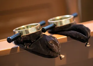 Zwei Kollektenbeutel liegen auf einer Kirchenbank.