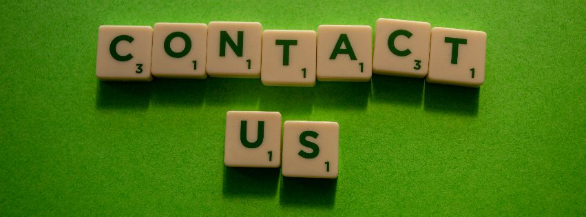 Scrabble-Steine sind auf grünem Hintergrund zu den Worten "Contact us" gelegt.